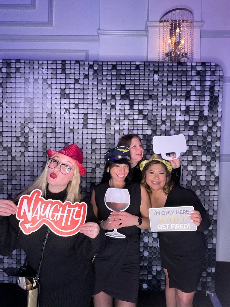 Collègues avec accessoires devant la toile argentée du photobooth